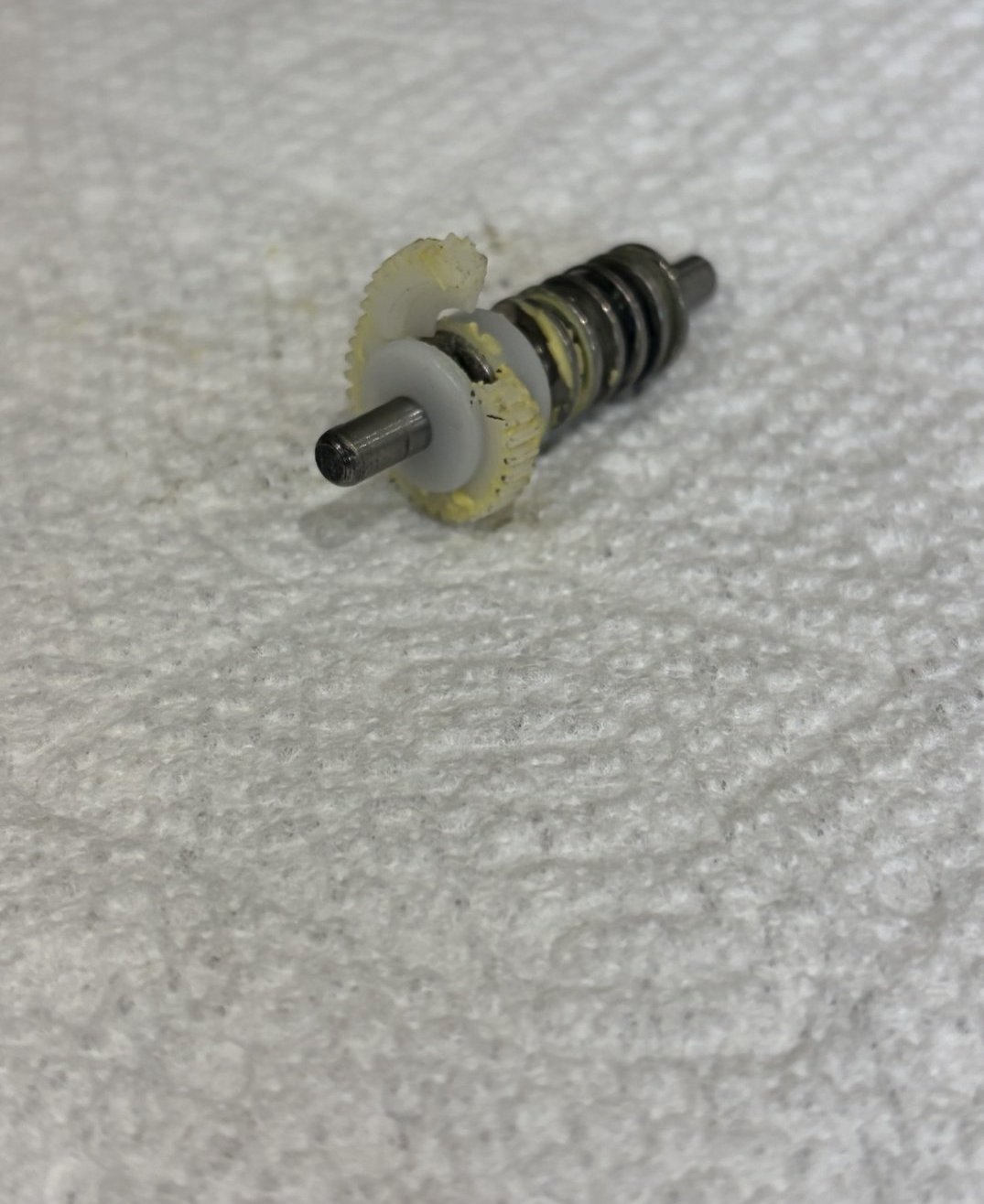 Broken plastic spur gear and spring assembly removed from a mirror motor housing